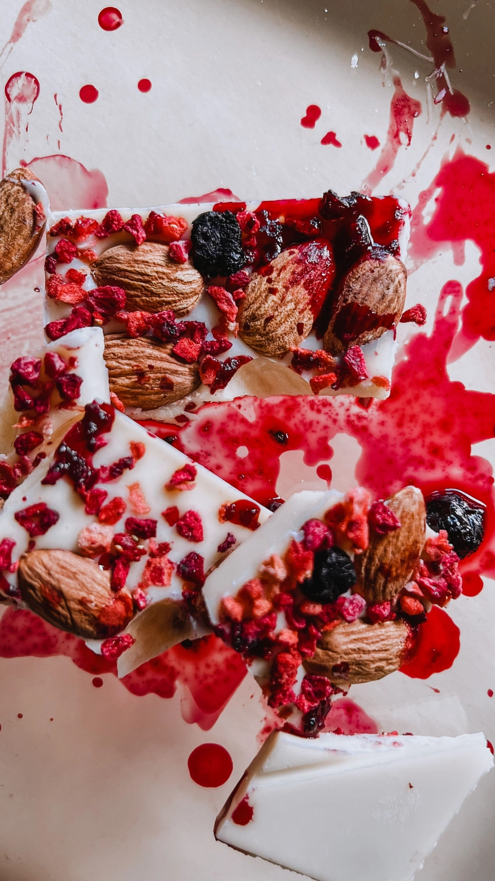 selbstgemachte Tafel weiße Schokolade mit Mandeln und roten Früchten zum genießen im Sommer