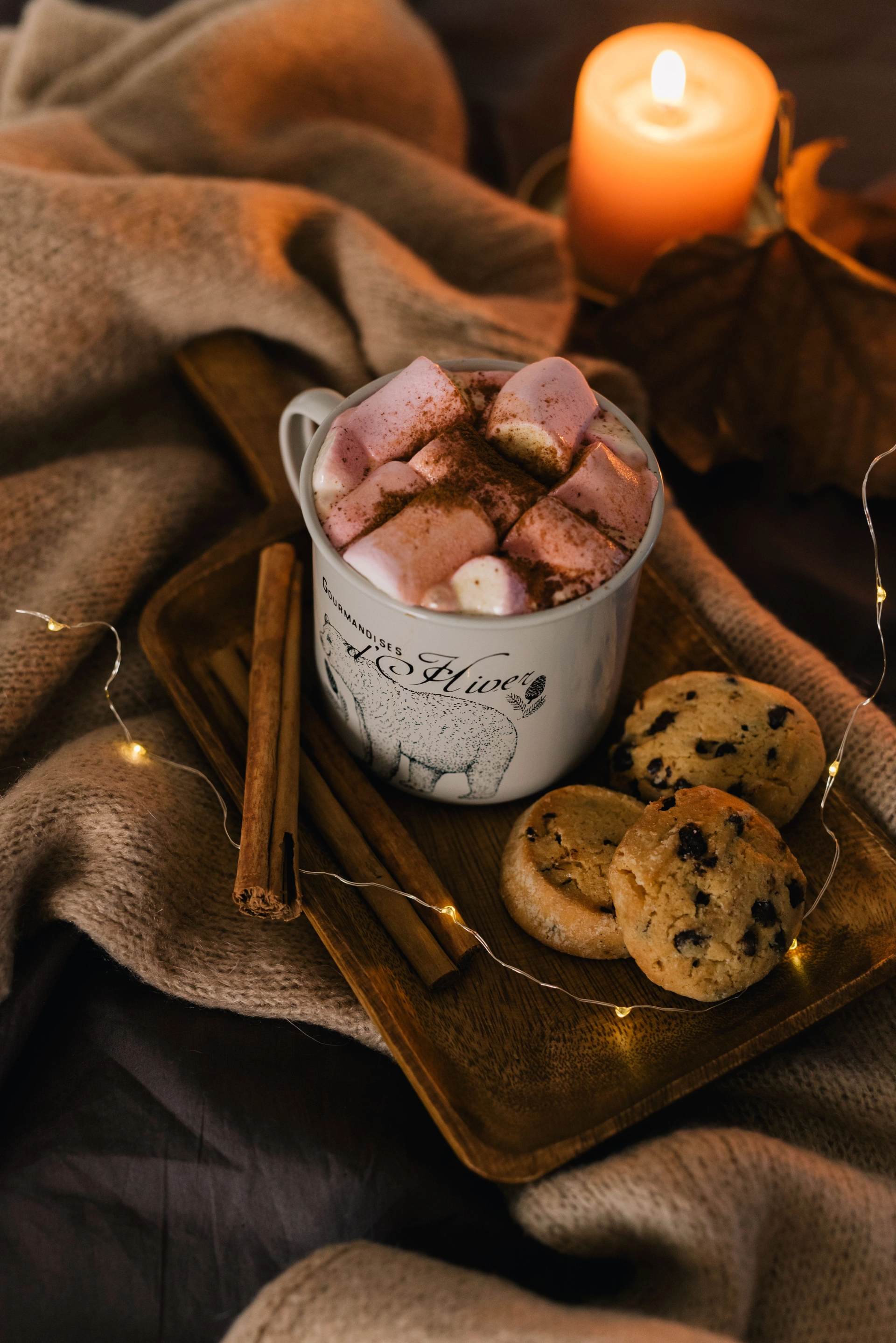 Tasse heiße Schokolade mit frischen Schokoladen-Cookies bei Kerzenlicht
